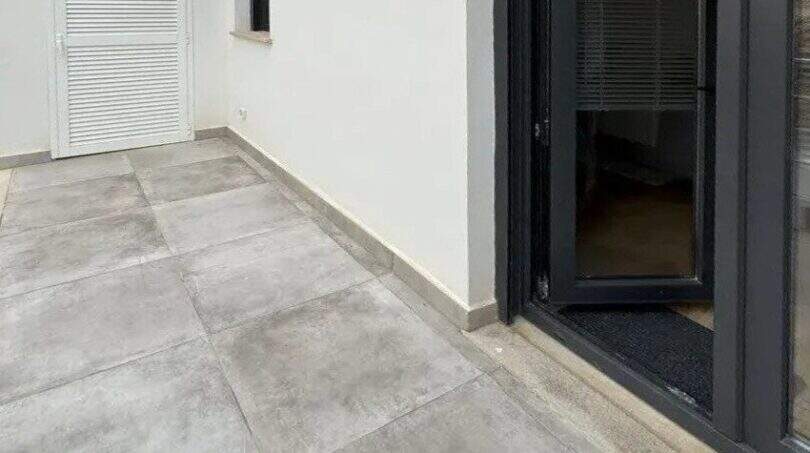 Moderne Dachterrasse mit Feinsteinzeugboden und großer Glasschiebetür zum Penthouse in Palma de Mallorca