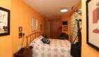 Bedroom with double bed, orange walls, wooden furniture and wall paintings in the building in Palma de Mallorca.