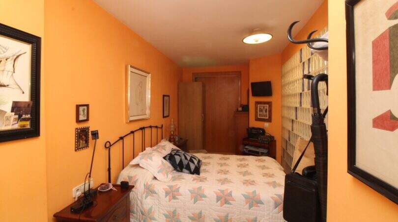 Bedroom with double bed, orange walls, wooden furniture and wall paintings in the building in Palma de Mallorca.