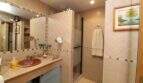 Elegant bathroom with marble sink, beige tile cladding, shower and wall mural in Palma de Mallorca