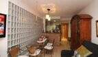 Living room with glass block wall, dining table, wooden cabinet and open kitchen in a building in Palma