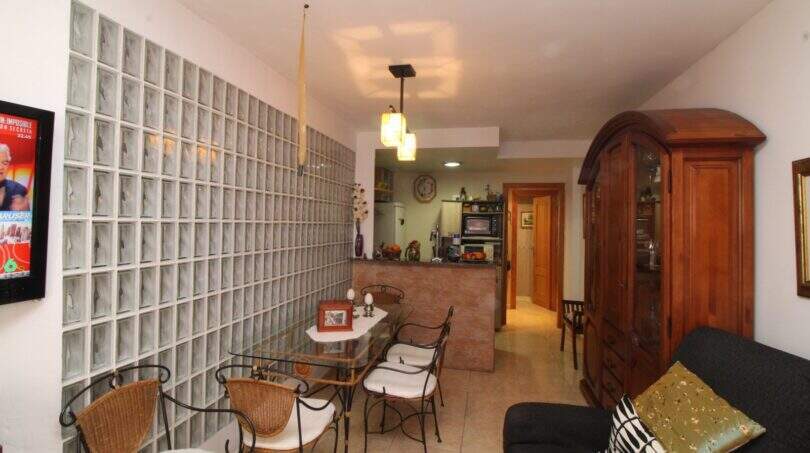 Living room with glass block wall, dining table, wooden cabinet and open kitchen in a building in Palma