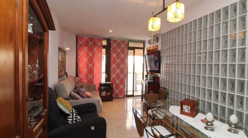 Living room with glass block wall, sofa landscape, dining table and balcony access in Palma de Mallorca