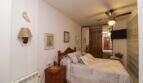 Bedroom with double bed, wooden furniture, ceiling fan and glass block wall in Palma de Mallorca