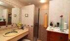 Bright bathroom with shower, beige tiles, decorative sink and wooden dresser in Palma de Mallorca.