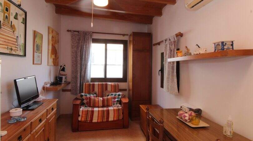 Cozy living room with wooden beam ceiling, armchair, TV and air conditioning in Palma de Mallorca
