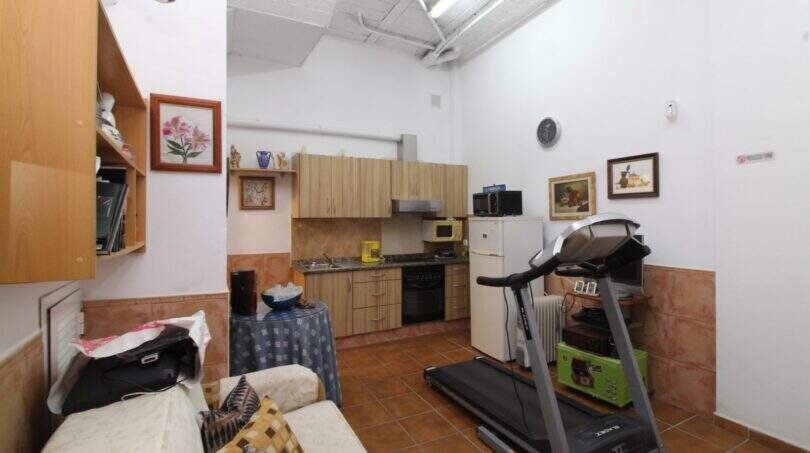 Open living area with kitchenette, treadmill and sofa in a building with development potential in Palma
