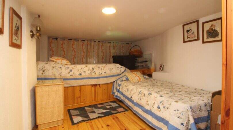 Bedroom with two single beds, wooden floor and wall paintings in a building in Palma de Mallorca.