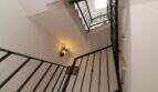 Staircase with black metal railing and wall light in a three-story building in Palma de Mallorca.