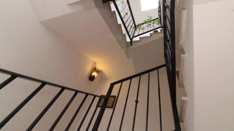 Staircase with black metal railing and wall light in a three-story building in Palma de Mallorca.