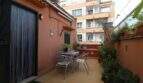 Sunny terrace with metal furniture and plants at a terracotta-colored building in Palma de Mallorca.