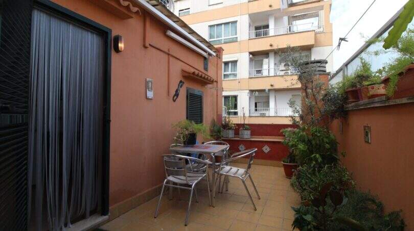 Sunny terrace with metal furniture and plants at a terracotta-colored building in Palma de Mallorca.