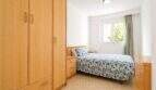 Helles Schlafzimmer der Wohnung in Portixol mit Holzschrank, Doppelbett und Fenster mit Grünblick.