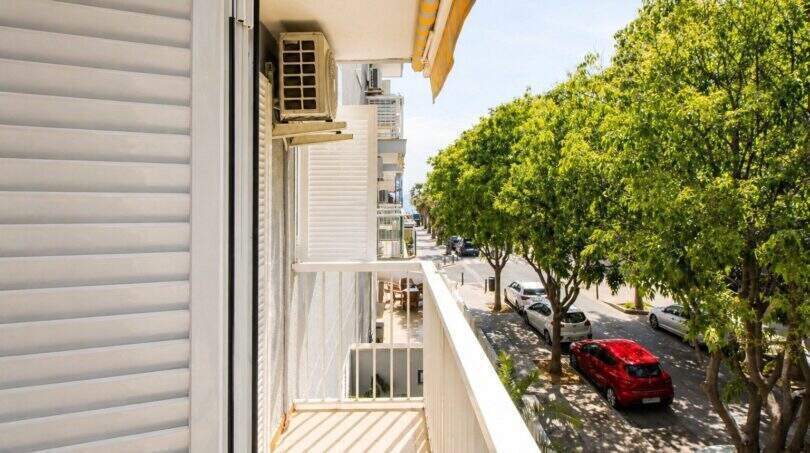 Balkon der Wohnung in Portixol mit Blick auf baumgesäumte Straße, Klimaanlage und Jalousien