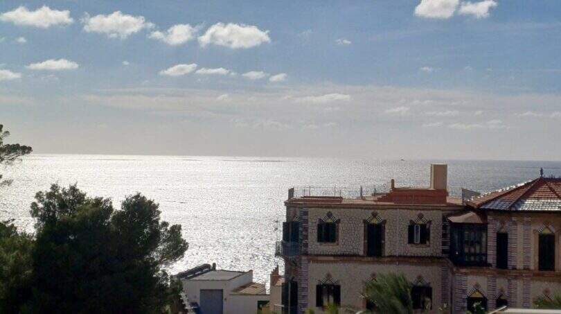 Meerblick vom Penthouse-Loft in Palma mit historischer Villa und glitzerndem Mittelmeer unter blauem Himmel