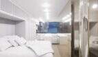 Helles Penthouse-Schlafzimmer mit weißem Doppelbett, modernem Design und Meerblick durch großes Panoramafenster