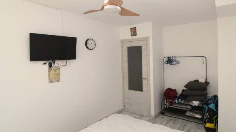 Helles Schlafzimmer mit Deckenventilator, Wand-TV, Uhr und Kleiderständer im Reihenhaus nahe Strand Palma