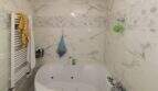 Badezimmer mit Whirlpool-Eckbadewanne, Marmorfliesen und Handtuchheizkörper im Reihenhaus Palma de Mallorca