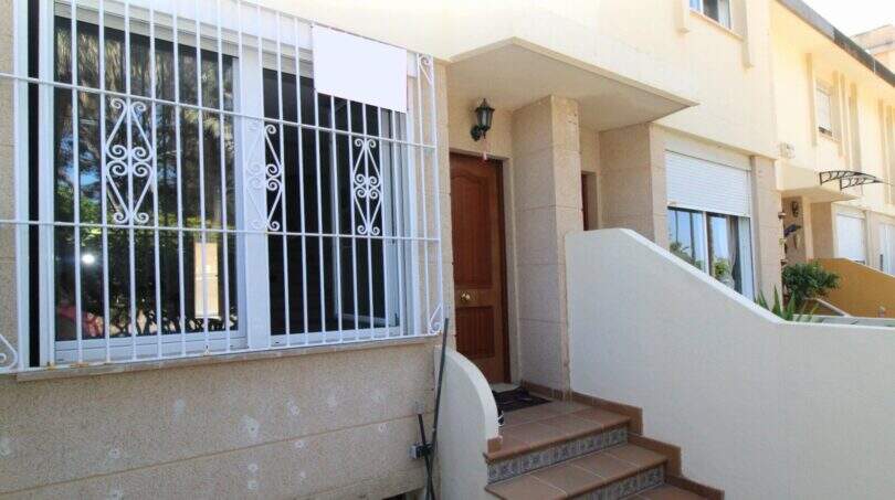 Hauseingang mit Treppe, Holztür und Sicherheitsgitter am Fenster eines Reihenhauses in Palma de Mallorca