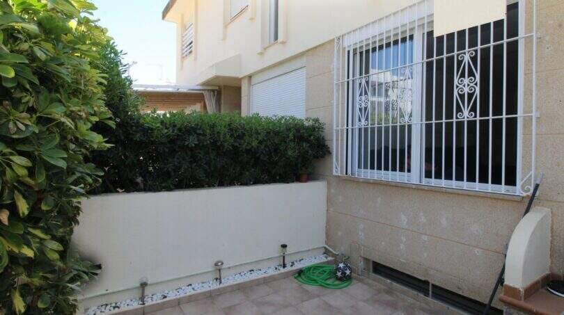 Kleiner Innenpatio mit Fliesenboden, Hecke, Eisengitter-Fenstern und Gartenbeleuchtung eines Reihenhauses in Palma