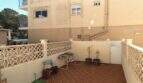 Überdachte Terrasse des Reihenhauses in Palma mit Ziergeländer, Topfpflanzen und Fliesenboden.