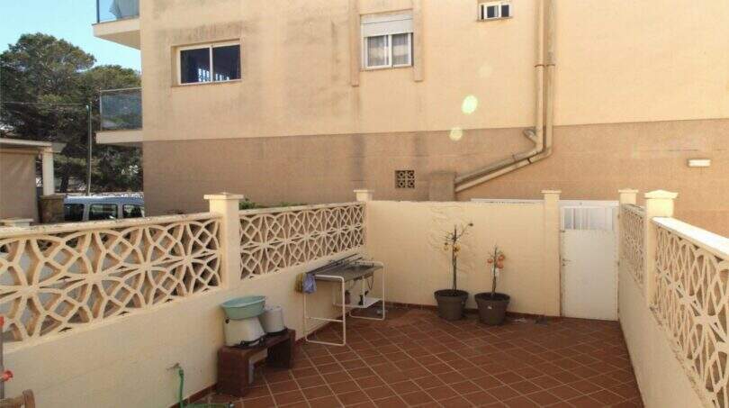 Überdachte Terrasse des Reihenhauses in Palma mit Ziergeländer, Topfpflanzen und Fliesenboden.