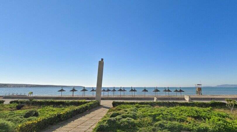 Strandblick mit Sonnenschirmen und blauem Meer, direkt vor dem Reihenhaus in Palma de Mallorca.