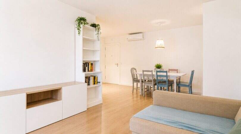 Heller Wohn-Essbereich mit Parkettboden, weißem Bücherregal und bunten Stühlen in exklusiver Wohnung Palma