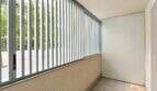 Überdachter Balkon mit mintfarbenen Metallstreben, Fliesenboden und Blick auf begrünte Umgebung in Palma