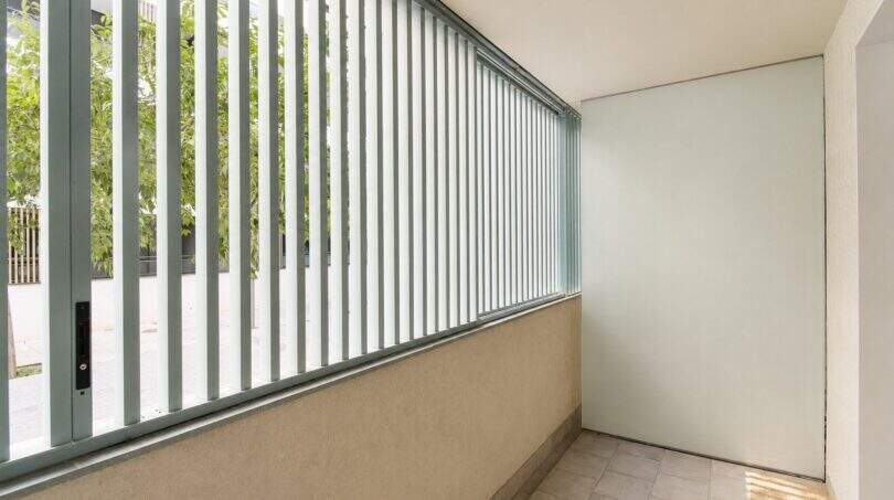 Überdachter Balkon mit mintfarbenen Metallstreben, Fliesenboden und Blick auf begrünte Umgebung in Palma
