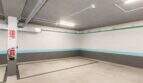Privater Tiefgaragenstellplatz der Luxuswohnung in Palma mit Betonboden, Feuerlöscher und moderner Beleuchtung.