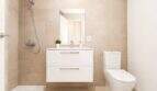 Modernes Badezimmer der Wohnung in Palma mit beigen Fliesen, schwebendem Waschtisch, Dusche und WC.