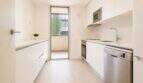 Moderne weiße Küche mit Einbaugeräten, Balkonzugang und natürlichem Licht in exklusiver Wohnung Palma