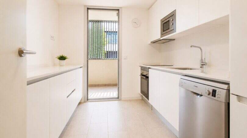 Moderne weiße Küche mit Einbaugeräten, Balkonzugang und natürlichem Licht in exklusiver Wohnung Palma