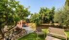 Sonniger Garten der Finca mit Sitzbereich, Obstbäumen und Kinderspielhaus nahe Palma de Mallorca.