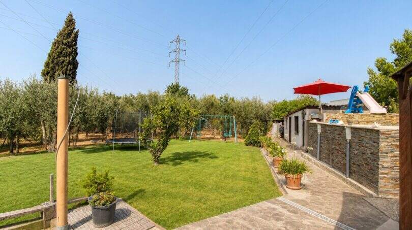 Gepflegter Garten mit Rasenfläche, Schaukel, Trampolin und Sonnenschirm der Finca bei Palma de Mallorca