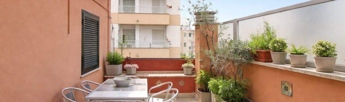 Sonnige Dachterrasse mit Esstisch, Stühlen und Pflanzen, Blick auf umliegende Gebäude in Palma de Mallorca.