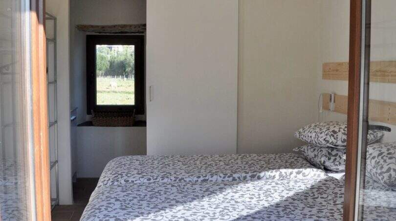 Schlafzimmer der Finca Campanet mit Doppelbett, Holzbalkendecke, Deckenventilator und Schiebetür zum Bad