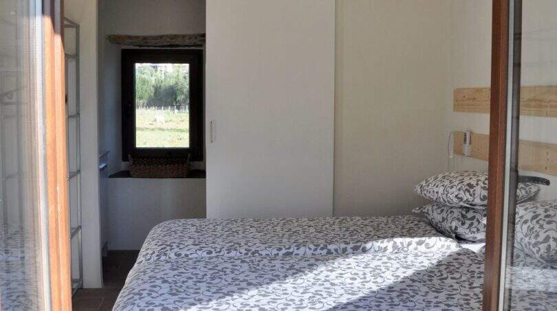 Schlafzimmer der Finca in Campanet mit Doppelbett, Schiebtür, Holzbalkendecke und Deckenventilator.