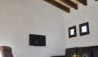 Wohnzimmer der Finca Campanet mit Holzbalkendecke, Deckenventilator, Ledersofa und Kuhfellteppich.