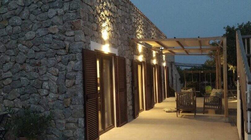 Finca Campanet: Beleuchtete Natursteinterrasse mit Holzläden und Pergola im Abendlicht