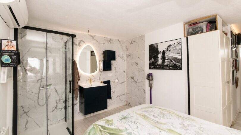Modernes Schlafzimmer mit begehbarer Dusche, Marmorwänden und beleuchtetem Spiegel in Finca bei Palma