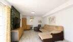 Helles Wohnzimmer der Finca mit Ecksofa, TV-Wand, Tropentapete und Klimaanlage nahe Palma.
