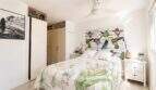 Helles Schlafzimmer der Finca mit floralem Bettbezug, Kolibri-Kopfteil und Deckenventilator.