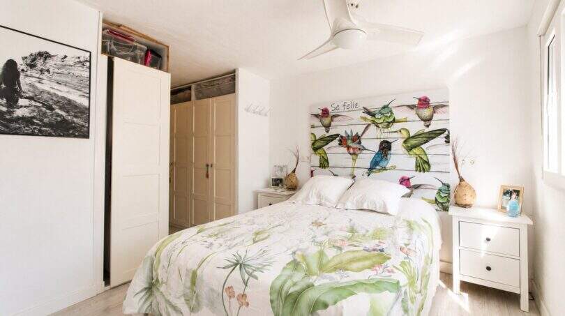 Helles Schlafzimmer der Finca mit floralem Bettbezug, Kolibri-Kopfteil und Deckenventilator.