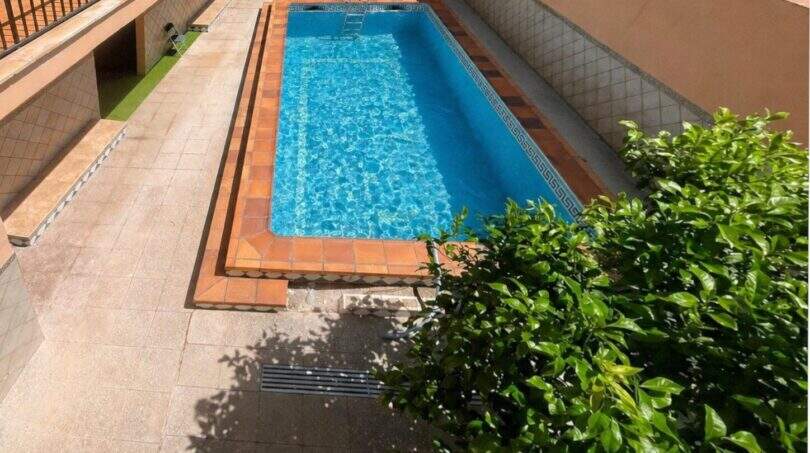 Rechteckiger Pool mit blauem Wasser und Terrakotta-Fliesen im Innenhof der Wohnanlage in Palma de Mallorca