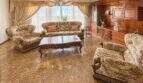 Elegantes Wohnzimmer mit Marmorboden, klassischen Sofas, Holzschrankwand und Kronleuchter in Palma-Wohnung.