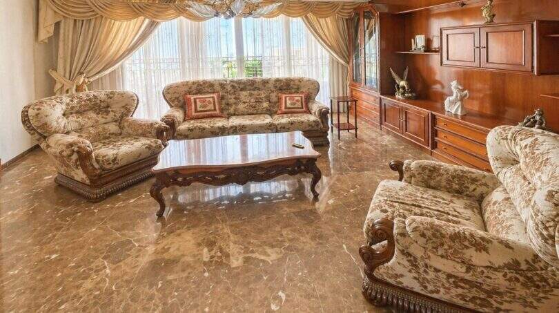 Elegantes Wohnzimmer mit Marmorboden, klassischen Sofas, Holzschrankwand und Kronleuchter in Palma-Wohnung.