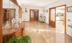 Elegant living area with marble floors, wood paneling and view into kitchen, apartment Palma de Mallorca