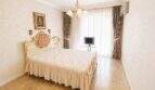 Elegantes Schlafzimmer mit Barockbett, Kronleuchter, Flachbildschirm und bodenlangen Vorhängen in Palma-Wohnung.